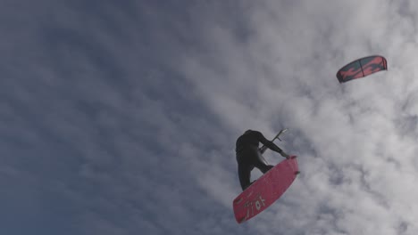 skilled kiteboarder jumping and spinning over the water.