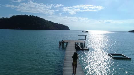 Chica-Asiática-En-Forma-Caminando-En-Un-Muelle-En-El-Océano-En-Una-Isla-Tropical,-Koh-Kood,-Tailandia