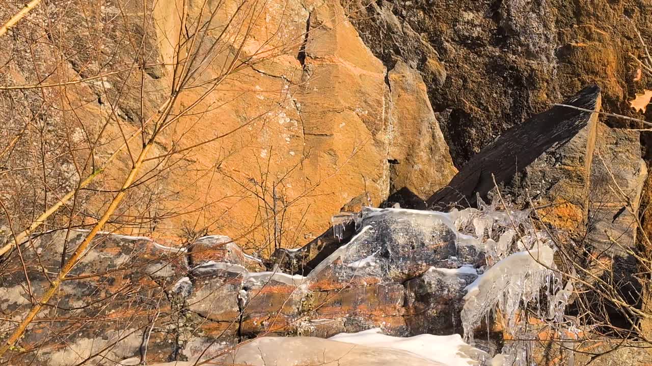 Paljon massiivisia jääpuikkoja sulamassa kevätauringossa vuorenrinteellä kirkkaan sinisen taivaan alla. Video on kuvattu 60 kuvaa sekunnissa, ja se on 23,976 kertaa hidastettu, joten voit päättää, miten haluat käyttää sitä.