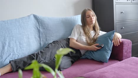 young woman relaxing on the sofa and watching a film at home, in slow motion