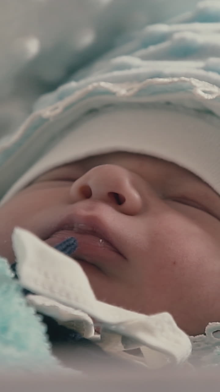 adorable little newborn baby in warm blue clothes sleeps on soft blanket in light room at home extreme close view
