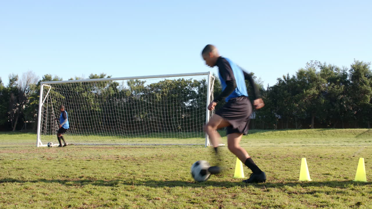 Playing soccer, two men practicing goalkeeping and shooting on field