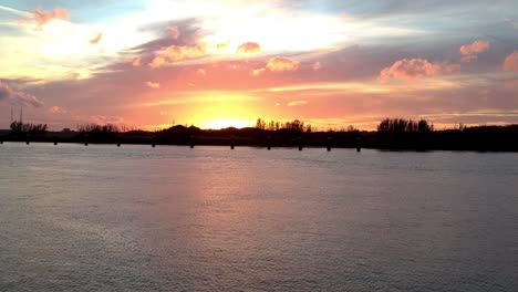 silhouetted river shore against a beautiful red-gold sunset