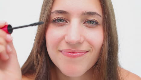 Joyful-brunette-applying-mascara-on-her-eyelashes