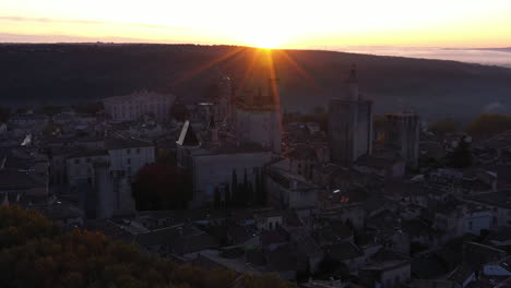 Fliegen-In-Richtung-Schloss-Uzès-Mit-Der-Aufgehenden-Sonne-Im-Hintergrund,-Wunderschöne-Luftaufnahme