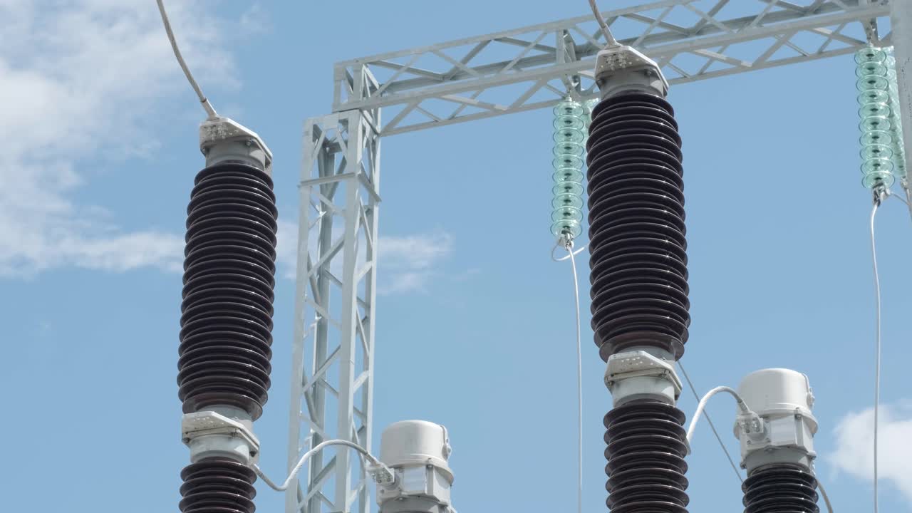Many high voltage electrical insulators in power substation against blue sky background