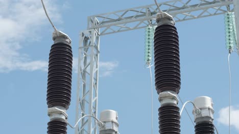 many high voltage electrical insulators in power substation against blue sky background