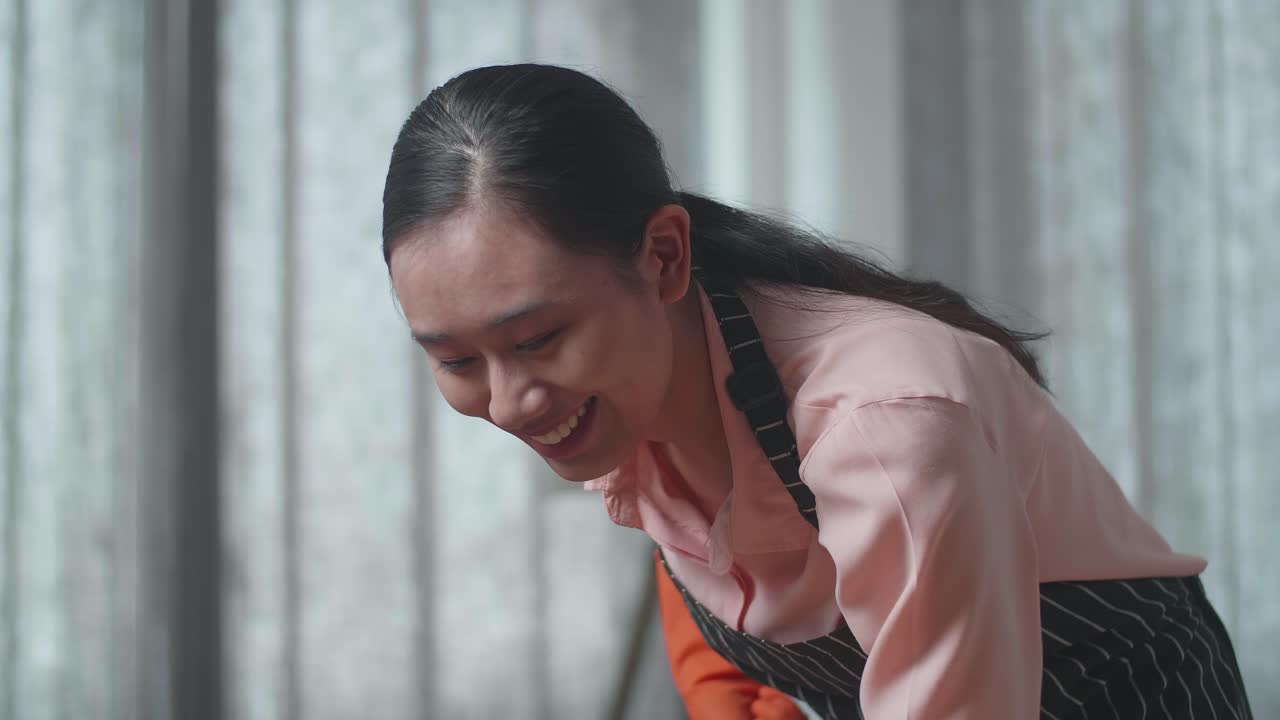 행복한 젊은 여성이 집을 청소하고 있습니다.