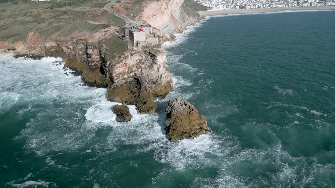 impresionantes olas marinas salpicando la orilla del acantilado y el fuerte de san miguel arcángel en nazare, leiria, portugal