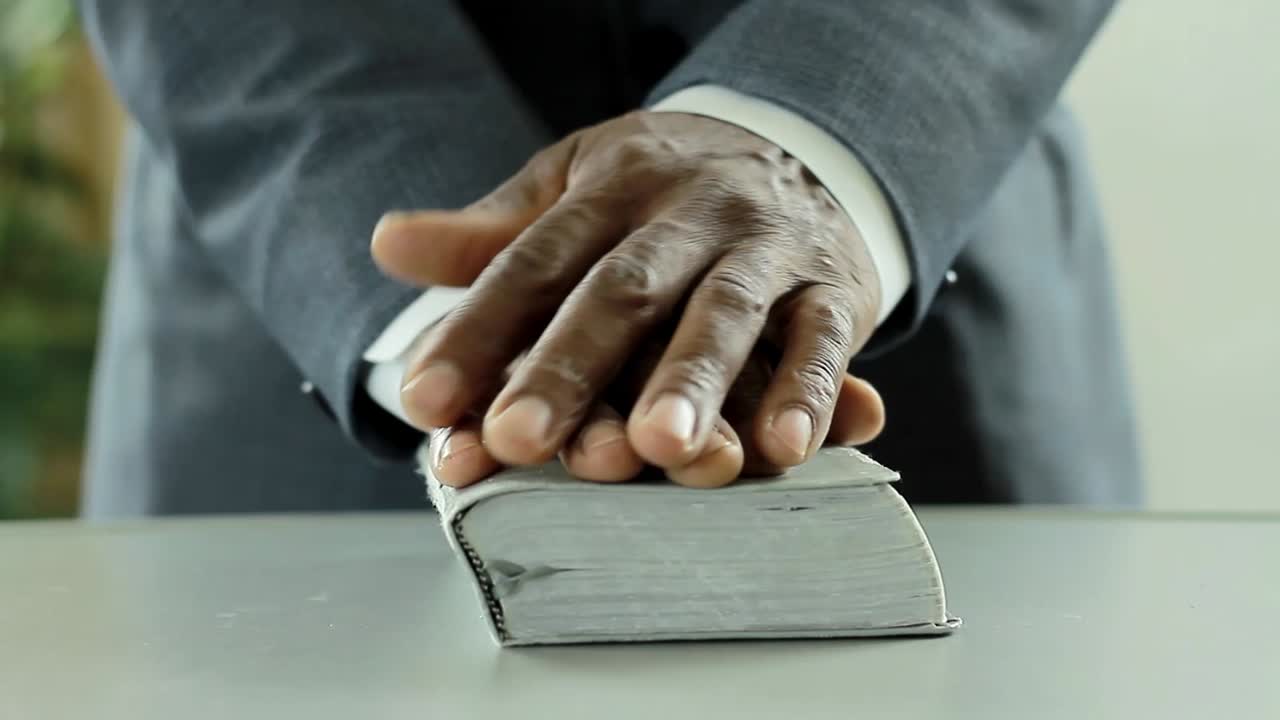 hombre negro orando a dios con la biblia en las manos hombre caribeño orando con el fondo con la gente stock video stock footage