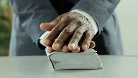 black-man-praying-to-god-with-bible-in-hands-caribbean-man-praying-with-background-with-people-stock-video-stock-footage