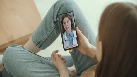 Female-using-online-chat-to-talk-with-family-therapist-and-checks-possible-symptoms-during-pandemic-of-coronavirus.-Woman-using-medical-app-on-smartphone-consulting-with-doctor-via-video-conference.