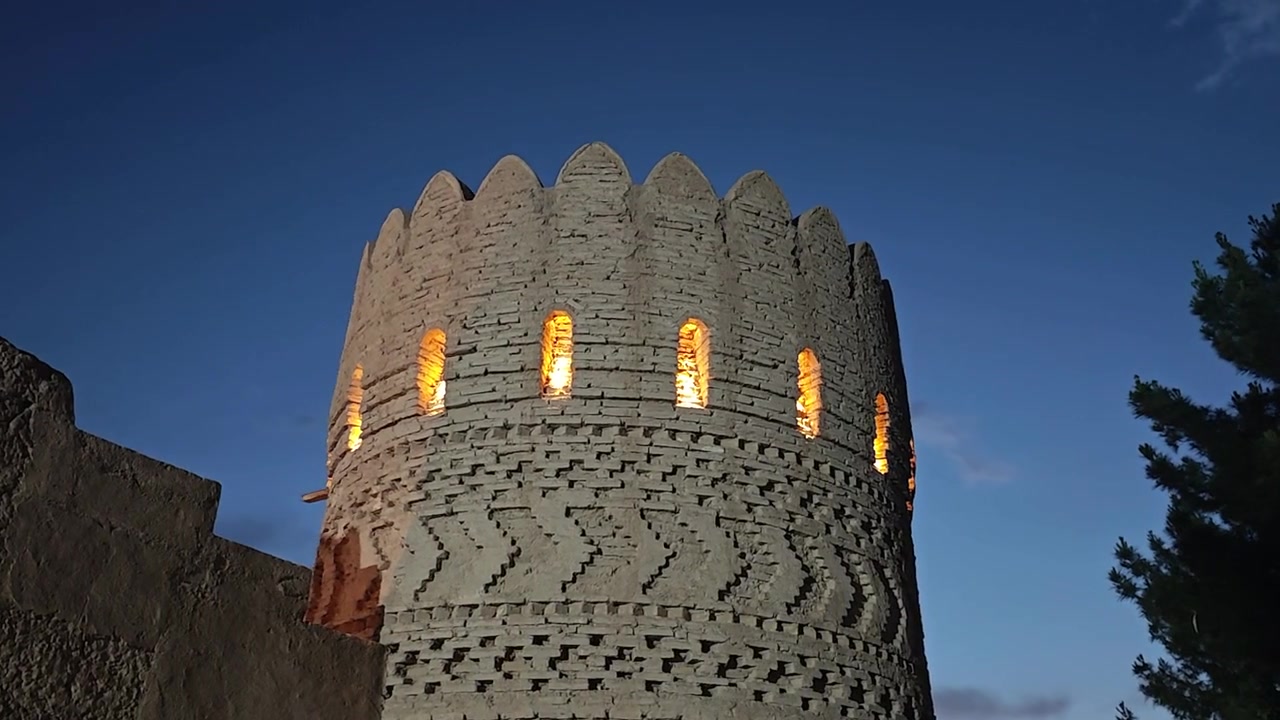 Alacakaranlıkta aydınlatılmış antik tuğla gözetleme kulesi.