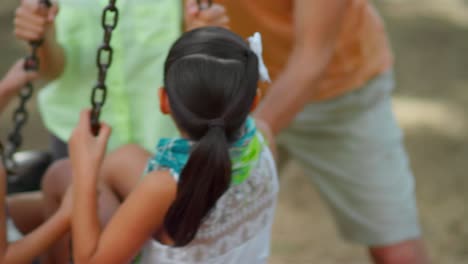 hermanas siendo empujadas por su padre en un columpio de neumáticos