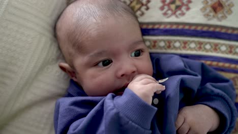 adorable bebé indio de 2 meses chupando la mano derecha mientras mira expresivamente