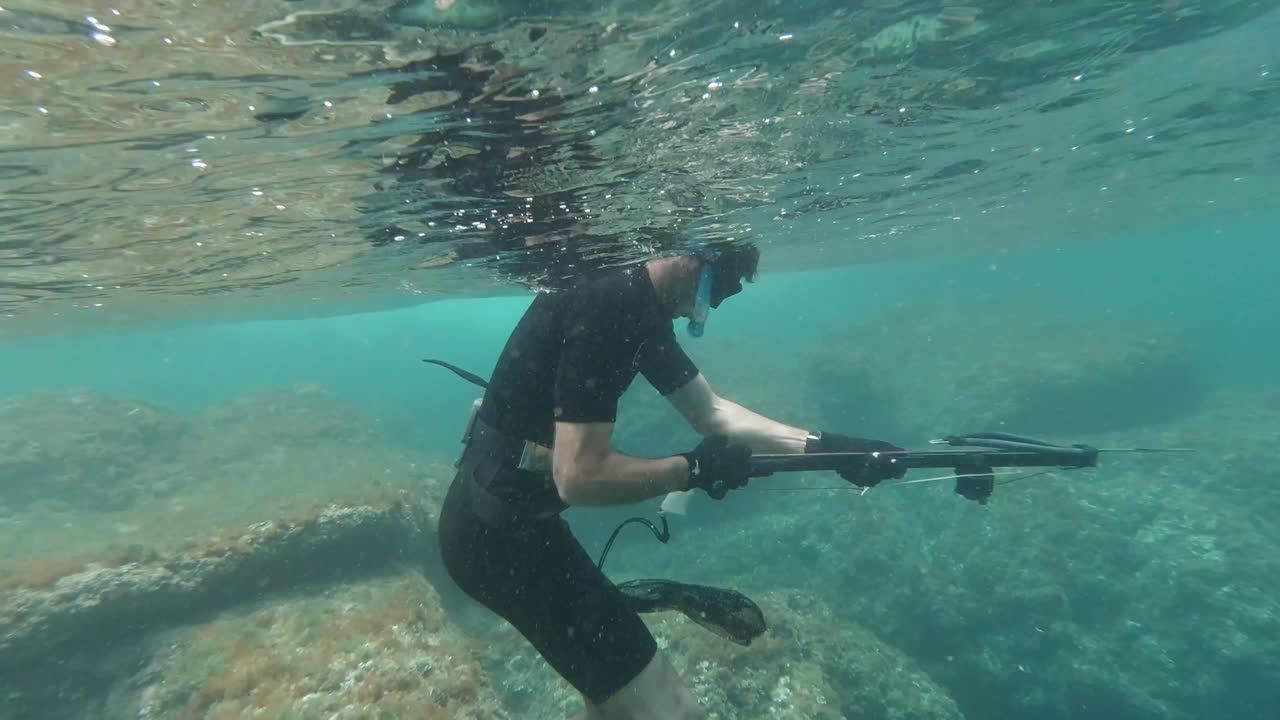 Spearfisher loading harpoon at shallow crystal clear water in the mediterranean sea