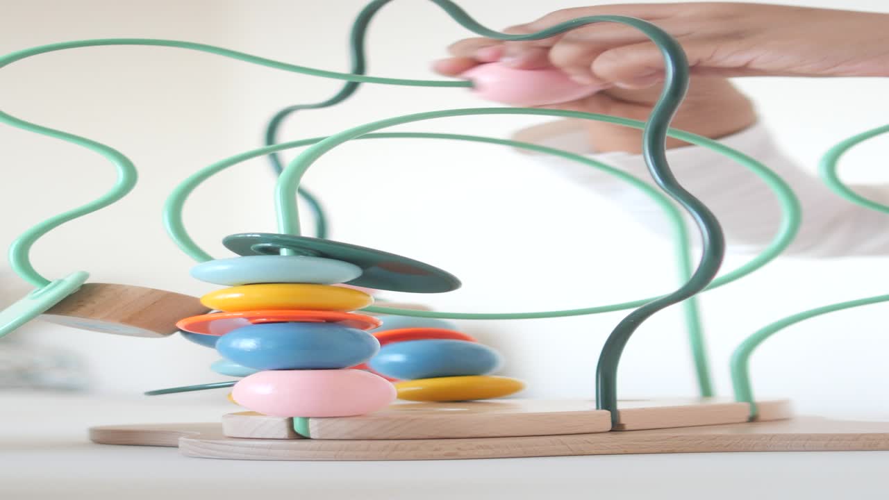 niño jugando con un colorido laberinto de cuentas de madera