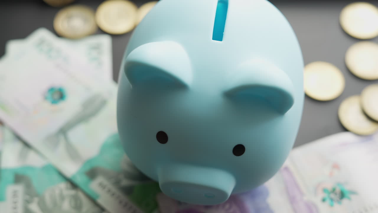Detailed view of a blue piggy bank surrounded by Colombian pesos and coins. This close-up shot highlights the concept of savings and financial planning. Natural lighting enhances the serene mood