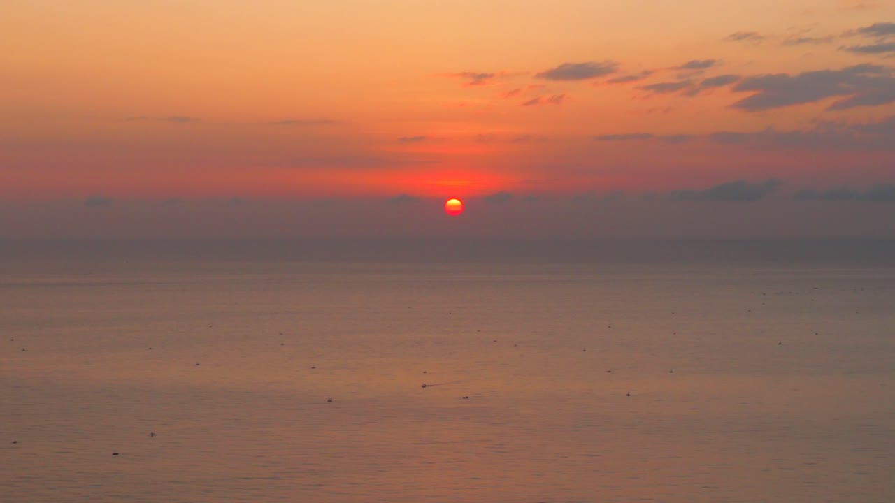 Aerial wide shot of the Amed coastline during sunrise with soft light over calm sea and fishing boats