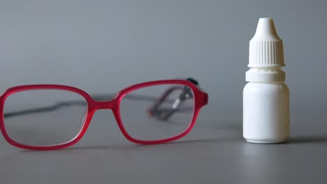 Close-up-of-eye-drop-bottle-and-eyeglass-on-black