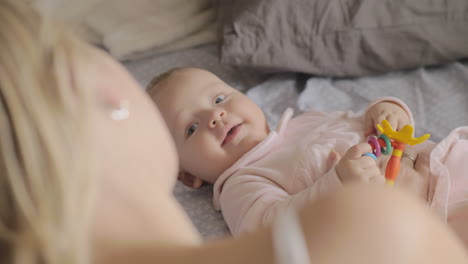 a cute baby girl lying on a back and smiling to her mother