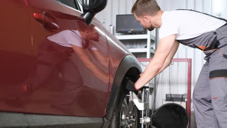mechanic performing wheel alignment on a car in a garage