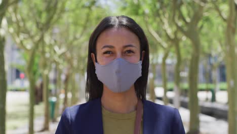 Portrait-of-african-american-woman-wearing-face-mask-looking-at-camera-in-street