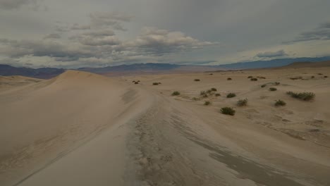 slow, right to left pan across wet sand dunes, with pastel mountains on the horizon