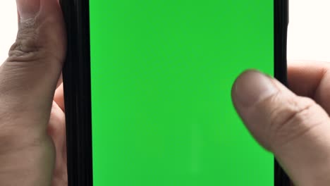 the man uses hand to touch mobile phone with green screen. learning at home concept.