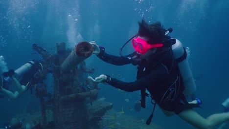 scuba divers exploring a historic shipwreck underwater