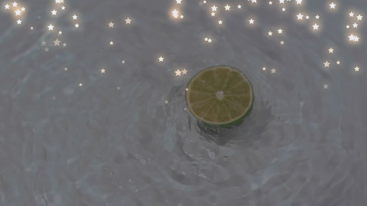 Upon dropping lime half-slice creating ripples while bobbing and sparkles drifting decorating scene