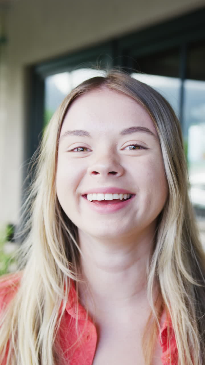 Vertical video of portrait of happy caucasian teenager girl at home, slow motion