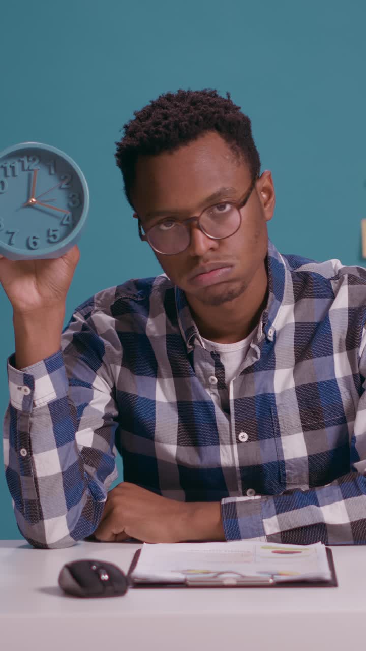 Man holding a clock at his desk