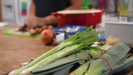 Lauch-Im-Vordergrund,-Dann-Ein-Fokus-Auf-Eine-Frau,-Die-Pilze-Für-Ein-Hausgemachtes-Suppenrezept-Schneidet