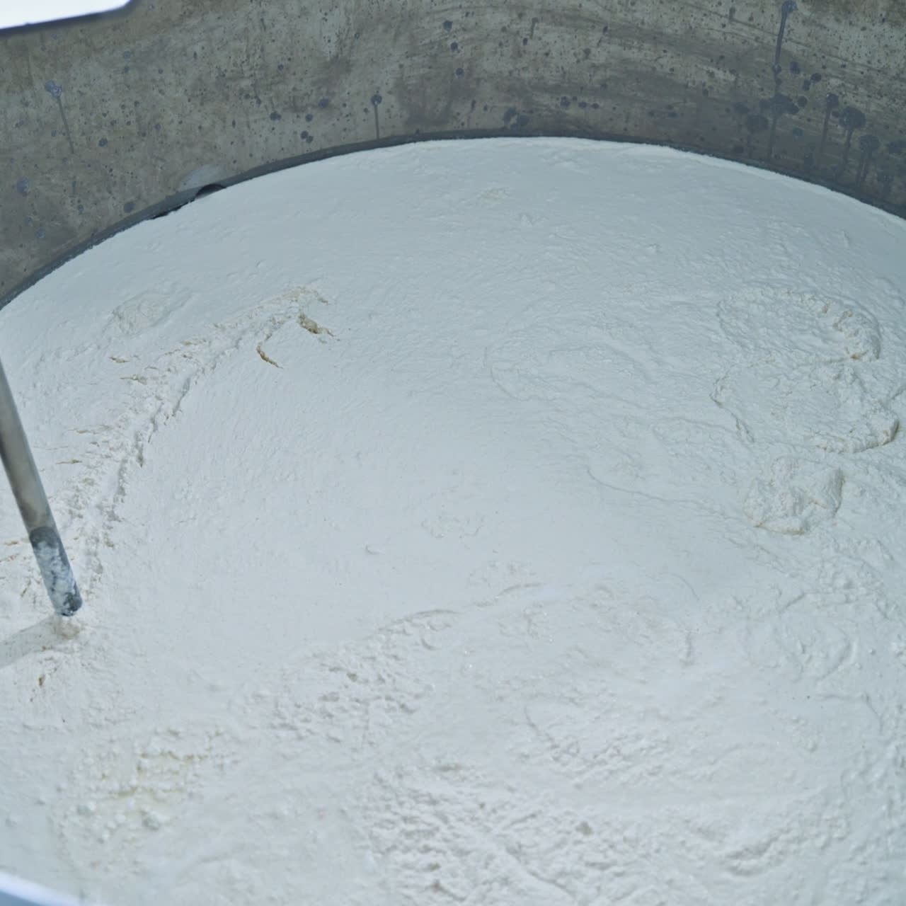 Slow motion of mixer in metal bowl for making cheese. Factory equipment. Metal mixing apparatus boils and mix milk for making cheese at milk products making factory.