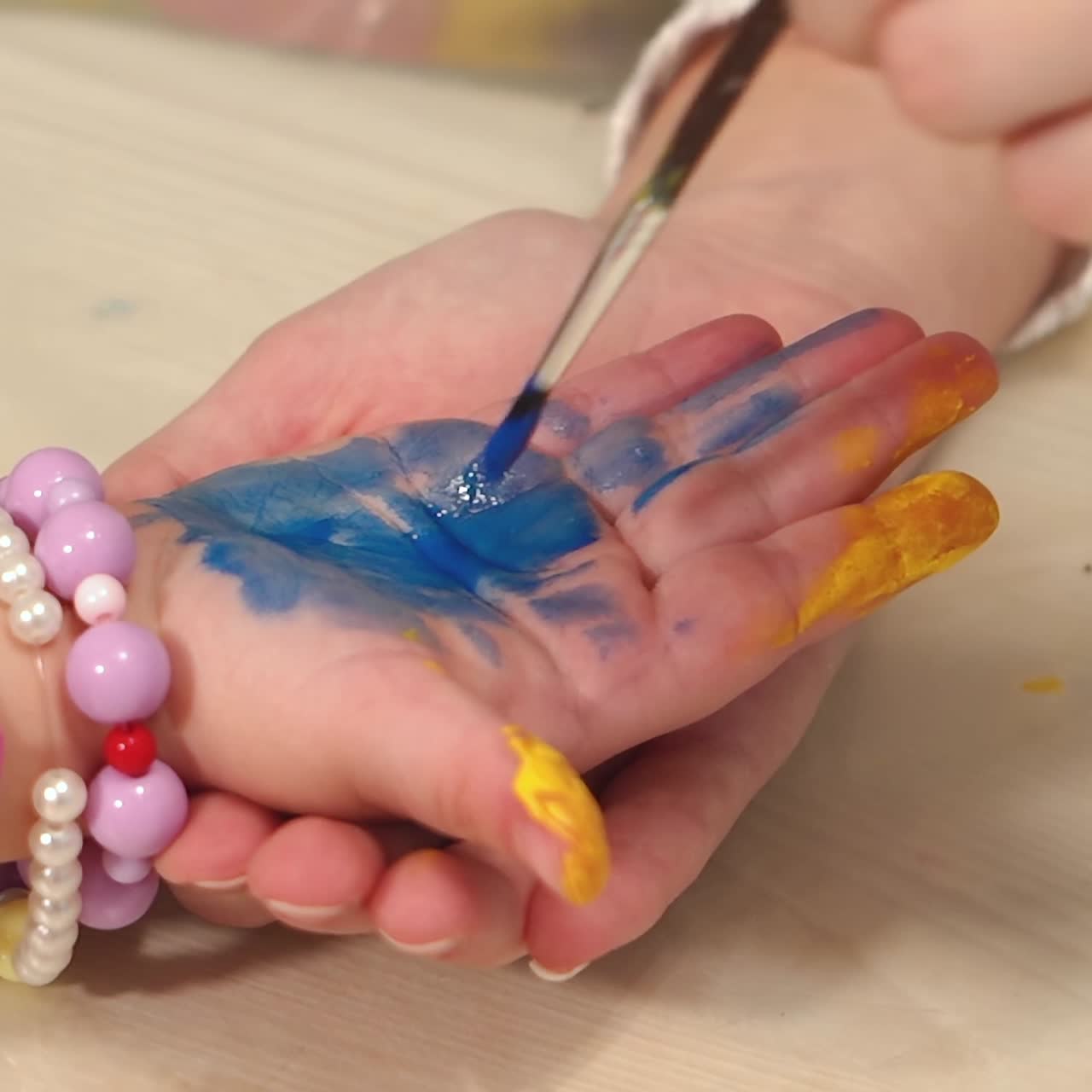 Funny child paints his hands with paint. Baby artist. Artist with dirty palms in paint.