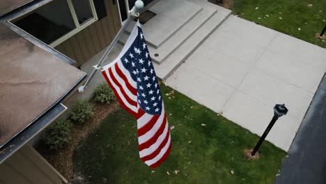 Hoher-Engel-Blickt-Auf-Eine-Amerikanische-Flagge,-Die-An-Einem-Haus-Hängt