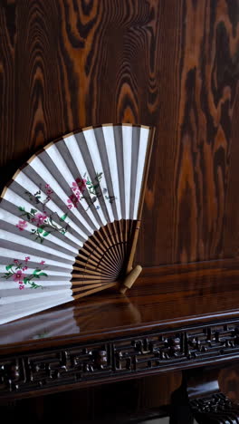 ornamental paper fan on a dark wooden table