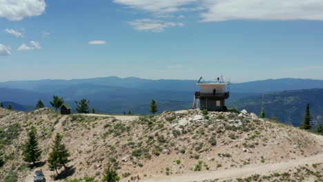 aerial circling fire lookout on top of mountain with people on lookout