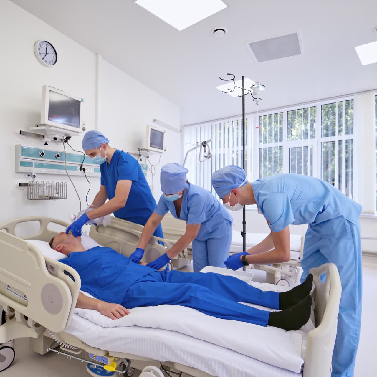 Contemporary light emergency room indoors. Specialist and practitioners giving resuscitation to a male patient in clinic.