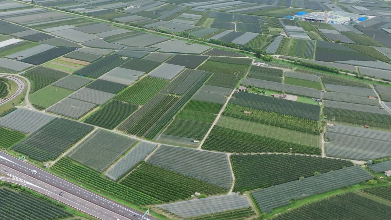 Aerial footage flying over a busy highway that cuts through vineyards in a valley in northern Italy.
