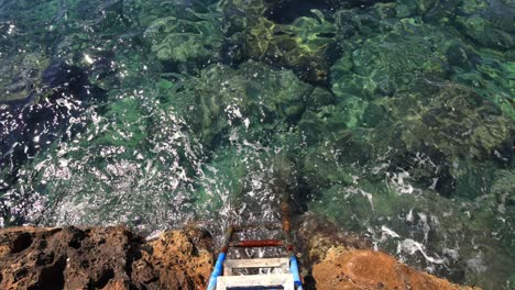 Top-down-shot-of-stairs-leading-the-path-into-the-ocean-water,-relaxing-waves-background-with-staircase