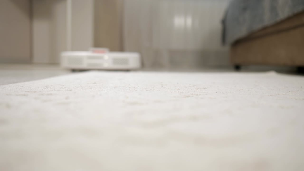 White robot vacuum cleaner cleans a light carpet