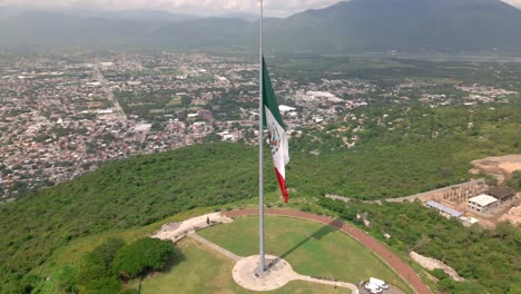 Giant-Mexican-flag-flies-in-the-wind-at-the-top-of-the-hill-in-Iguala,-Guerrero,-Mexico