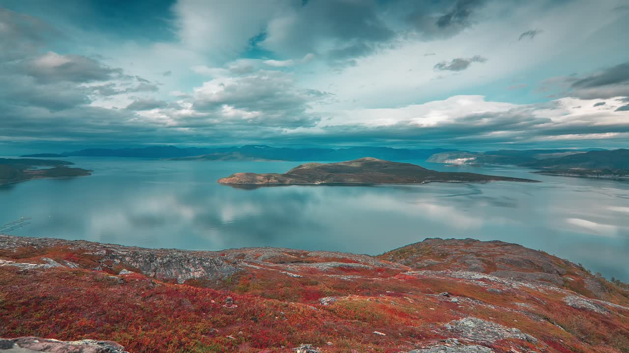 nubes tormentosas iluminadas por el sol de otoño giran sobre el tranquilo fiordo y las montañas en el video timelapse