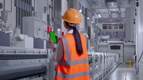 factory worker inspecting production line with smartphone