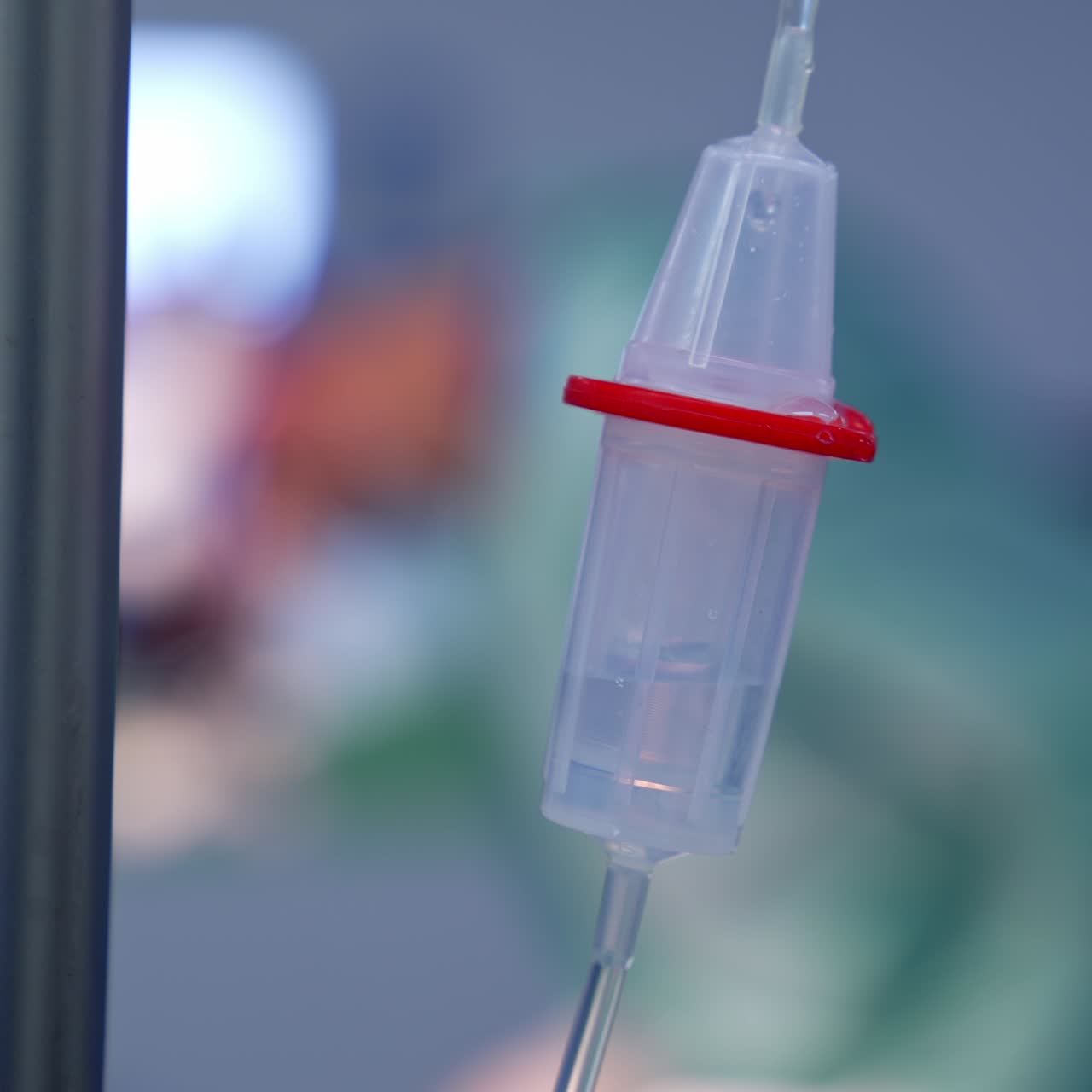 Liquid slowly dripping inside the drop counter. Close up. Intravenous drip in surgery room at operation. Blurred backdrop
