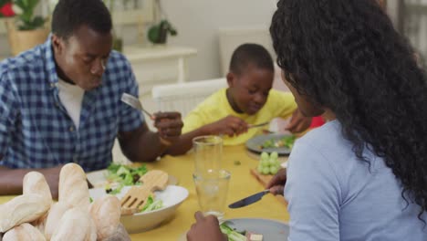 happy african american mother eating lunch with family at home