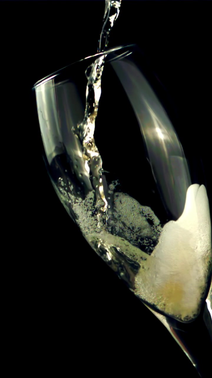 Versamento al rallentatore di champagne frizzante in un bicchiere su sfondo nero