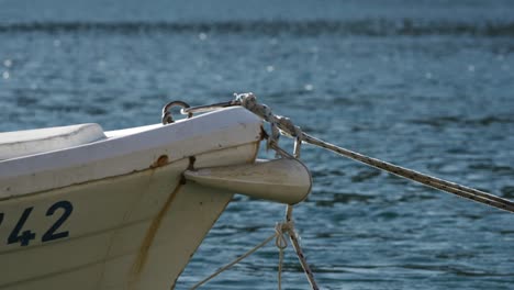 boat moored up on seaside harbour, closeup of rope anchor tied to boat